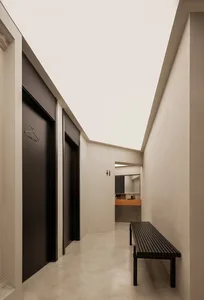 Modern, minimalist corridor with concrete and black materials, featuring industrial-style lighting and a waiting area.