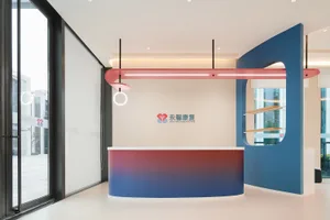 A modern reception desk with a red and blue gradient, a hanging light fixture, and a branded logo.