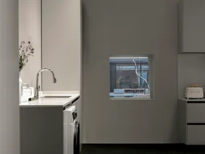 Modern kitchen with marble countertop and sink, featuring a window looking out to a pool and outdoor seating area.