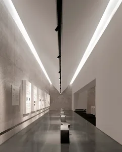 A spacious museum exhibition hall with polished concrete floors and minimalist exhibits.