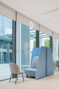 Modern office space featuring fabric seating, glass partitions, and metal accents.