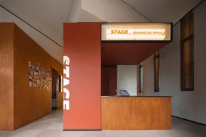 Modern interior design featuring a wooden reception desk with a stage area illuminated by a sign.