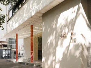 Modern retail storefront with white plaster exterior and red columns.