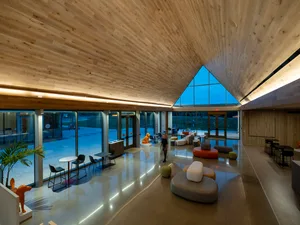 A spacious, modern lobby with a wooden ceiling and concrete floors features a variety of seating options.