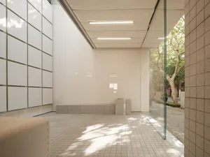 A minimalist interior space featuring concrete tiles and large windows.