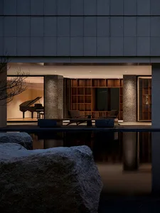 Modern minimalist living room featuring stone, wood, and stainless steel materials.