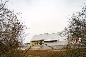 Modern building with a metal roof surrounded by trees.