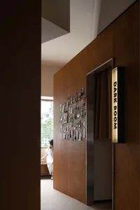 A dark room with wooden paneled walls featuring a collection of framed photographs on the left wall.