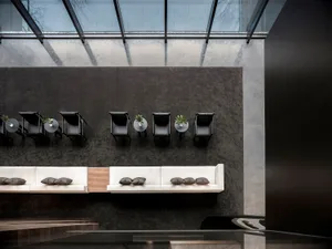 Modern office lounge area with concrete walls and glass partitions.