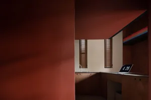 An interior office space featuring minimalist design with wooden cabinets and a laptop on a desk.