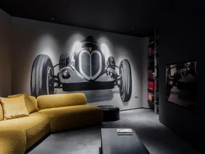 Industrially designed living room featuring a concrete floor, a yellow sofa, and a large black-and-white mural of a classic c