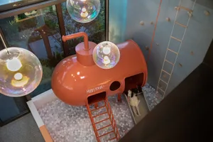 A child emerging from a ball pit slide designed to resemble a submersible
