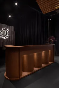 A contemporary, industrial-style reception desk crafted from copper, featuring sleek, cylindrical columns illuminated by warm