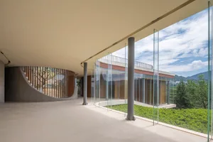 Modern architectural space featuring large glass panels and a curving staircase.