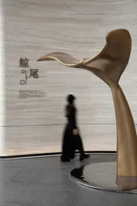 A futuristic, metal sculpture resembling a whale's tail accentuates a modern interior design space.