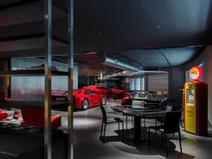 A modern garage exhibit showcasing black and red vehicles, with metallic glass and industrial lighting.