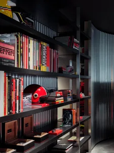 Modern home library with black metal shelves filled with books and racing helmets.