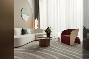 A modern interior of a living room with a white velvet couch, a marble coffee table, and a red and cream armchair.