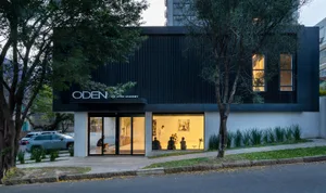 Modern metal-clad storefront for a jiu-jitsu academy with people practicing martial arts inside.
