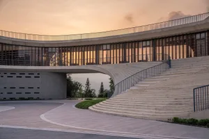 Modern building facade with concrete, glass, and wooden elements at dusk.
