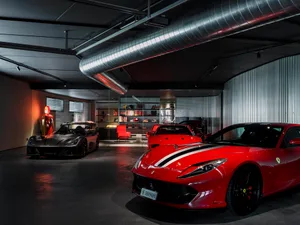 Well-lit car dealership with sleek metallic finishes, concrete flooring, and high glass elements