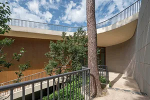Spiral staircase with concrete walls and railings surrounded by greenery, shot from above.