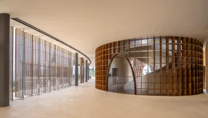 A modern interior space featuring a wooden spiral staircase with arches and a railing.