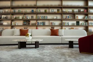 Library with modern furniture featuring marble coffee tables and a large bookshelf filled with books and decorative items.