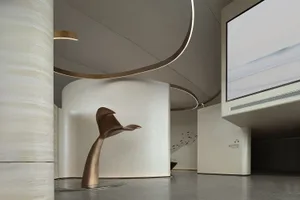 A modern lobby featuring a concrete wall and floor, with a large screen displaying a serene beach scene.