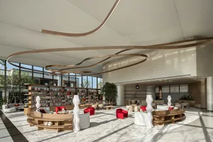 Modern lounge area with metal sculptures, concrete flooring, and glass walls