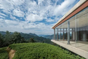 A modern residential terrace with glass walls overlooking green fields and mountains.