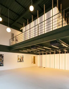 A minimalist interior space with a concrete floor, white walls, and exposed wooden beams.