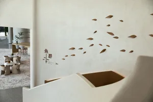 Modern restaurant interior with white concrete walls and a floating staircase.