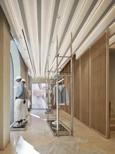 現代零售店內有白色天花板橫樑、木質牆板、穿著當代服裝的模特兒，以及服裝展示架