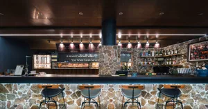 Food court with a stone wall, serving area, and bar stools for seating.