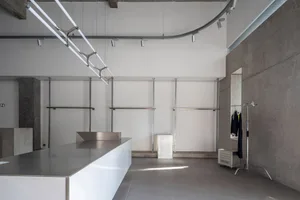 A minimalist office space with modern concrete walls and metal shelving.