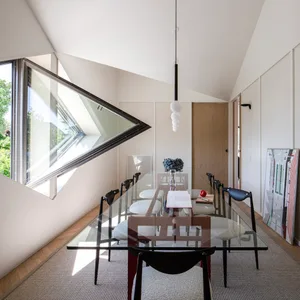Modern dining room featuring a sleek glass table and contemporary black and white chairs surrounded by minimalist decor and l