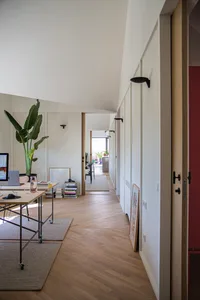 A modern home office with wooden flooring and walls, featuring a desk with a laptop and a green potted plant.