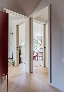 A modern living room with white walls, hardwood flooring, and a combination of wooden and glass furniture.