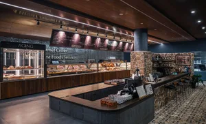 A retail meat market with stone walls, wood furnishings, and refrigeration displays showcasing various cuts of meat.