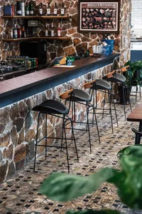 Industrial-style bar area with stone walls, featuring black stools and a rustic stone counter.
