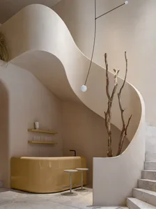 A minimalist bar area with a yellow bar counter, concrete stairs, and a dried plant.