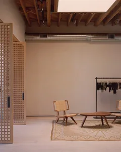 A minimalist retail store interior featuring a wooden floor, walls, and furniture.