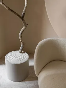 A modern chair with a circular, textured seat and a cylindrical, concrete base with a spiraled design, placed in a minimalist