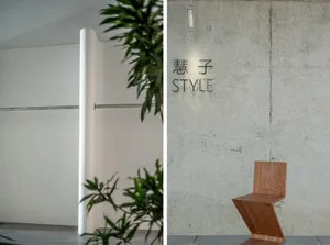 Modern, minimalist space with concrete walls and floor, featuring a unique wooden chair and green foliage.