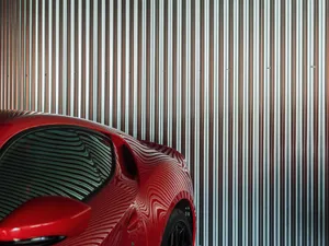 Red car parked beside metallic siding wall