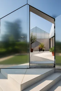 A modern glass exterior with a patio and potted plants.