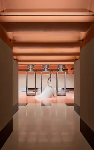 A woman wearing a white wedding dress stands in a modern interior.