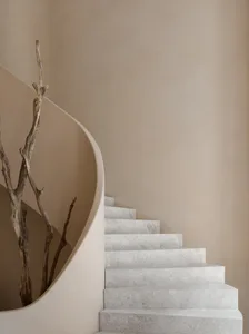 Modern staircase with concrete steps and wall, featuring organic branch as decoration.