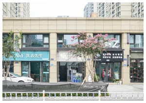 一排現代都市店面，展示各種服務業店家，周圍種植樹木與街道景觀